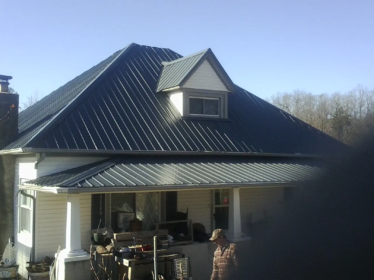 Dark blue standing seam metal roof with a dormer above a front porch in Berlin